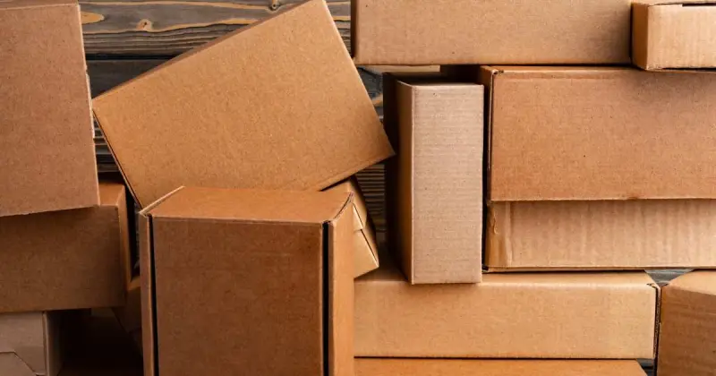 large pile of different sized brown cardboard boxes with dark wood background
