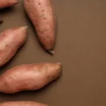 whole sweet potatoes scattered on brown tabletop