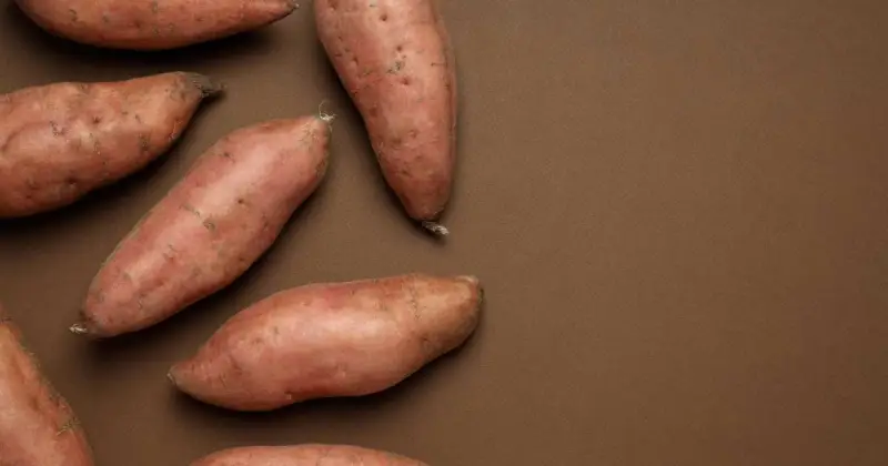 whole sweet potatoes scattered on brown tabletop