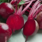 small batch of fresh red beets and green leaves on kitchen counter